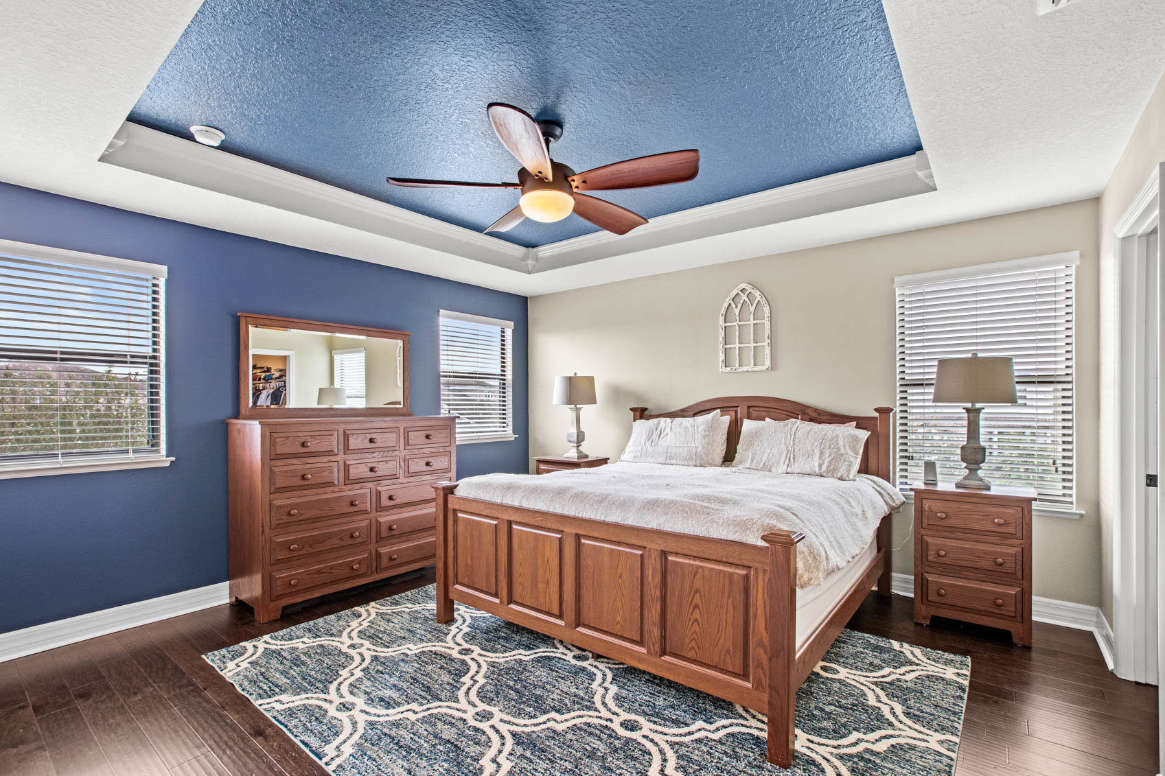 bedroom with blue ceiling and big white bed with cherry oak furniture